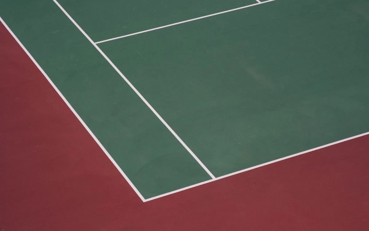 The corner of a hard court where the baseline meets the sideline, the kind of line a human being once watched for four hours at a time