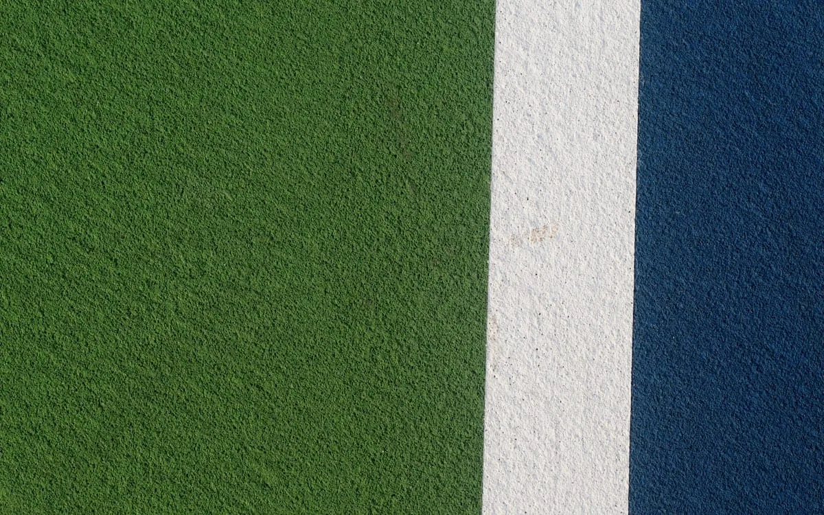 A close view of a hard court surface showing the green apron, a white line and the deep blue playing area, the colours of the US Open