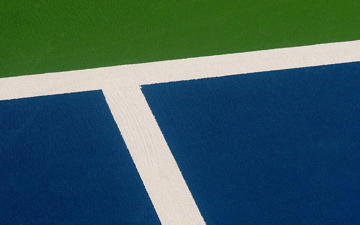 A blue hard court with green surround and white lines, the colours of the US Open